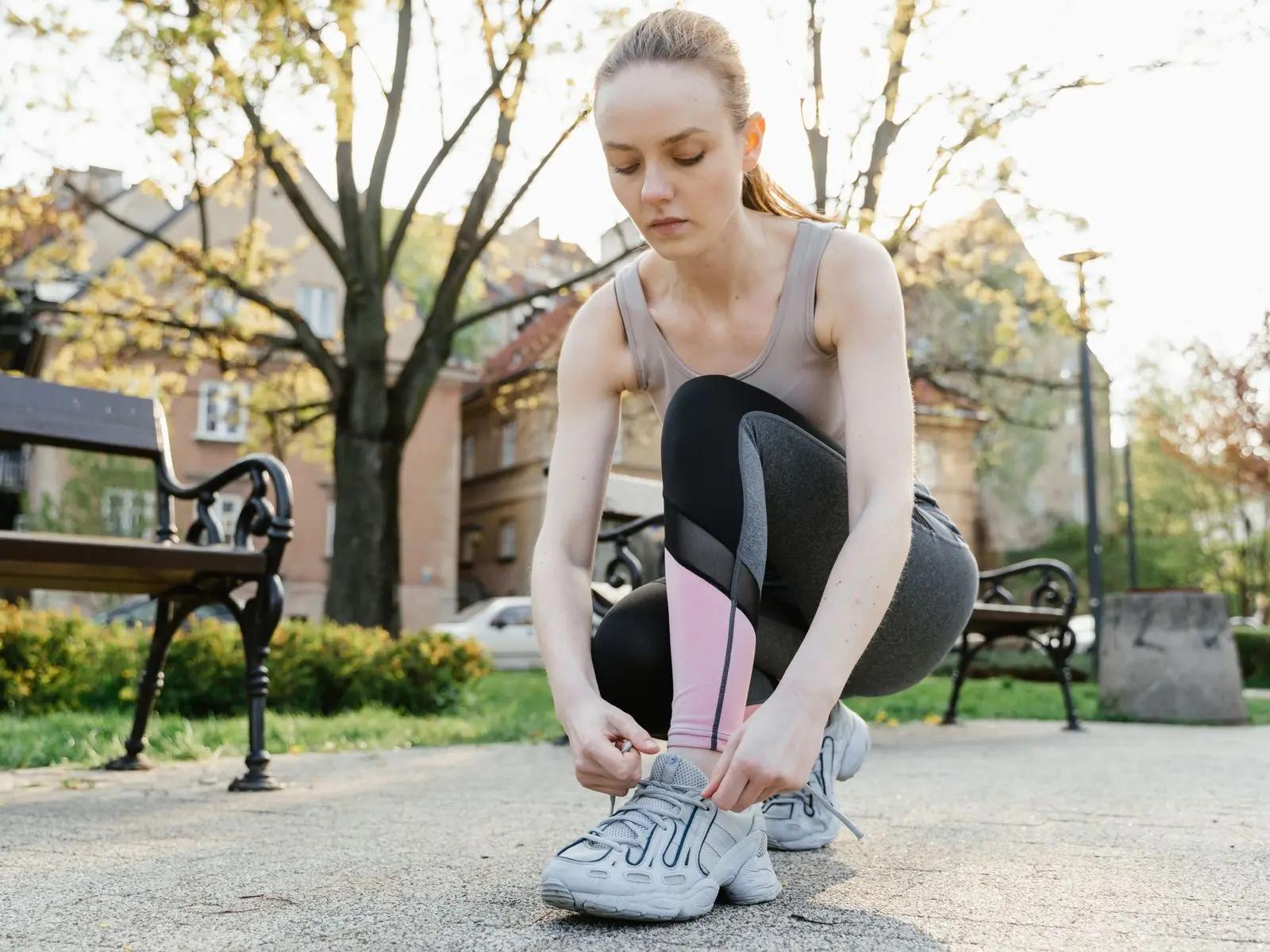 A woman tying her trainers in a park before a run