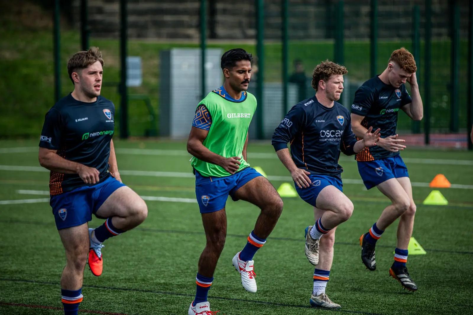 Rugby players warming up on an artificial pitch